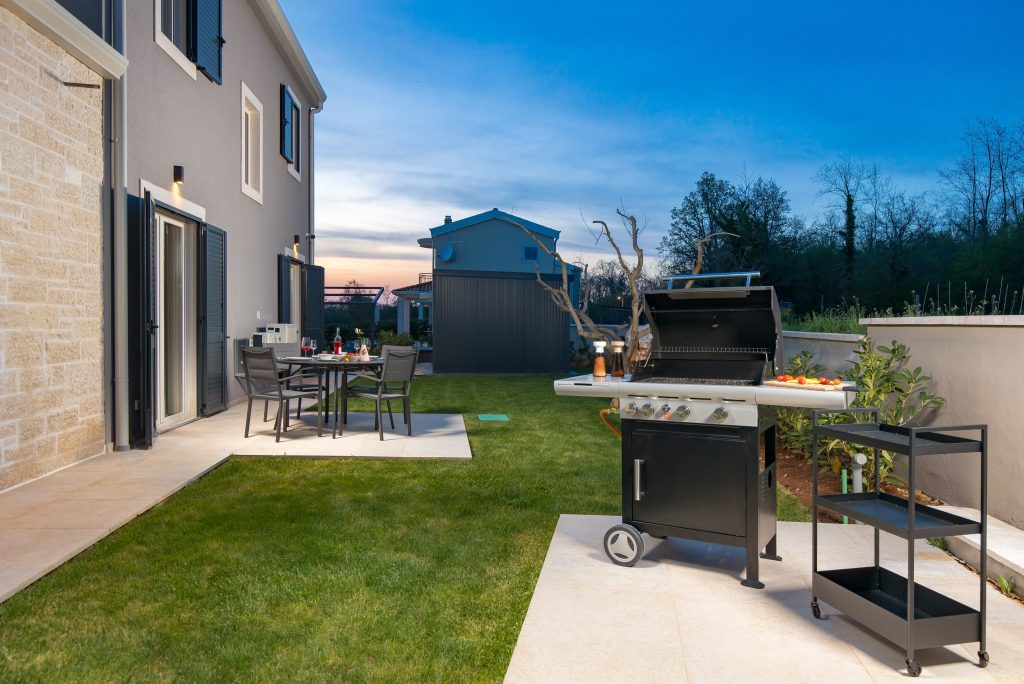 Barbecue grill and dining table in the garden at twilight