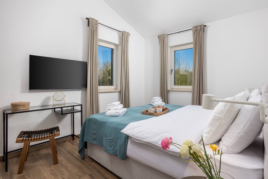 Bedroom with twin windows and flat-screen TV