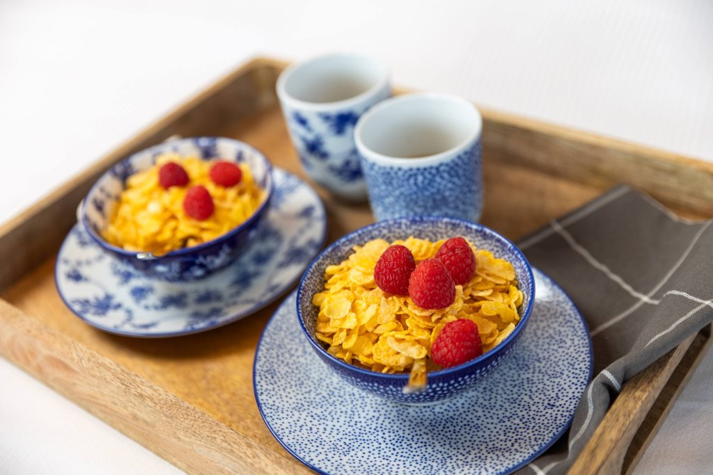 Breakfast tray with cereal and fresh berries in bed