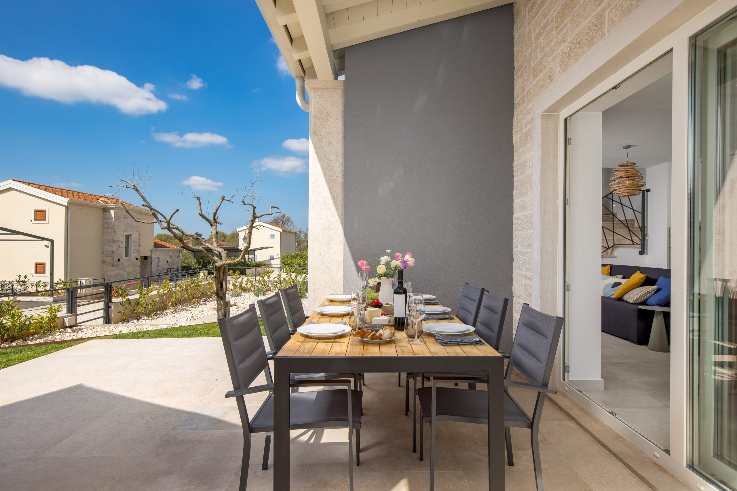 Covered terrace dining table set with wine and cheese
