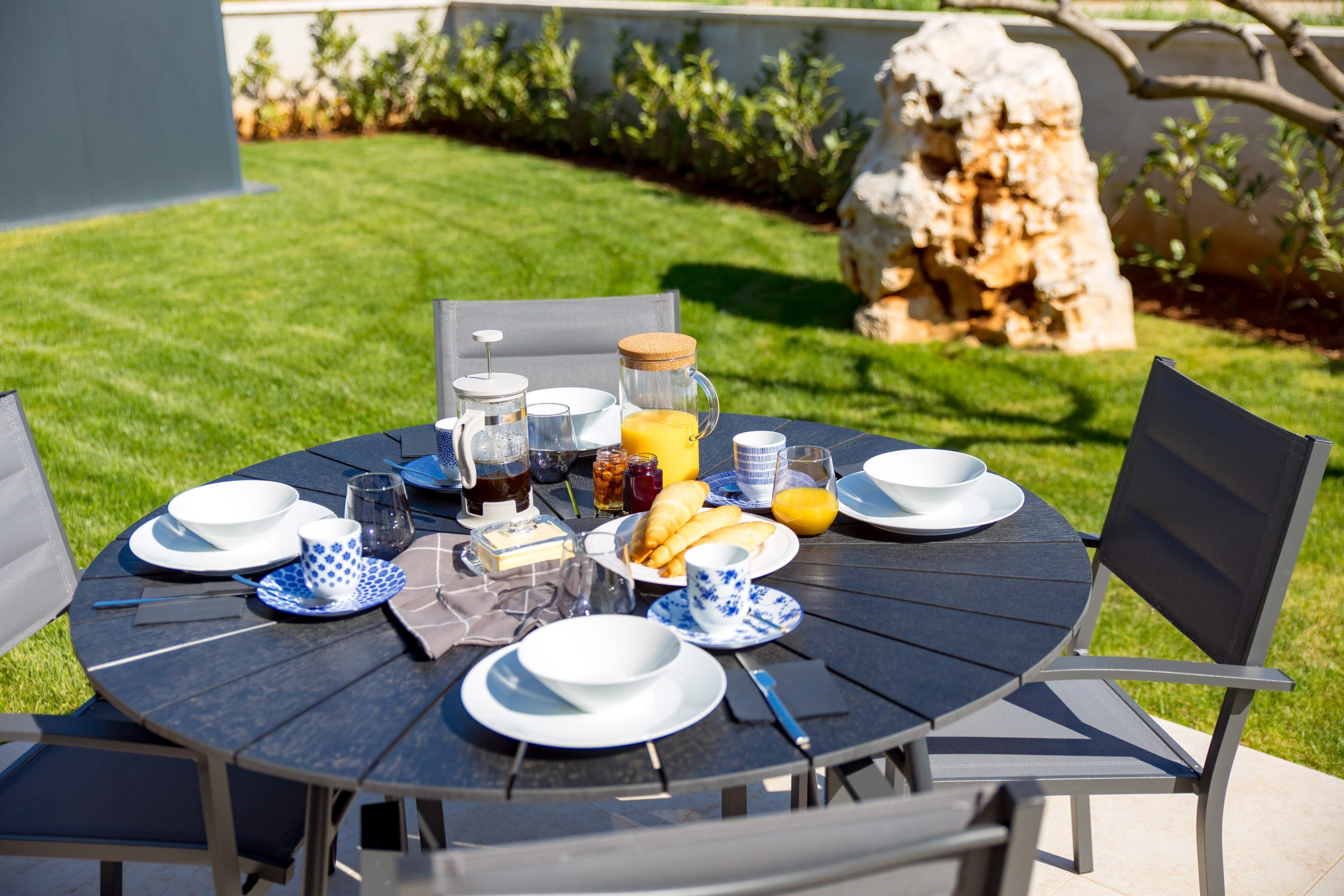 Outdoor breakfast table set with croissants and coffee