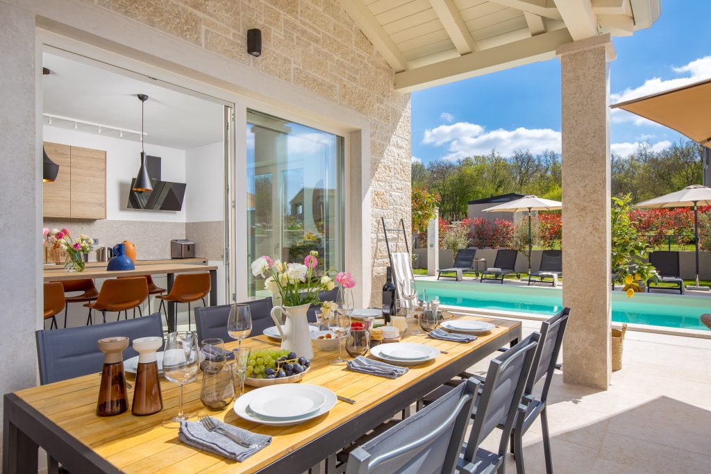 Outdoor dining terrace set for a meal with pool view