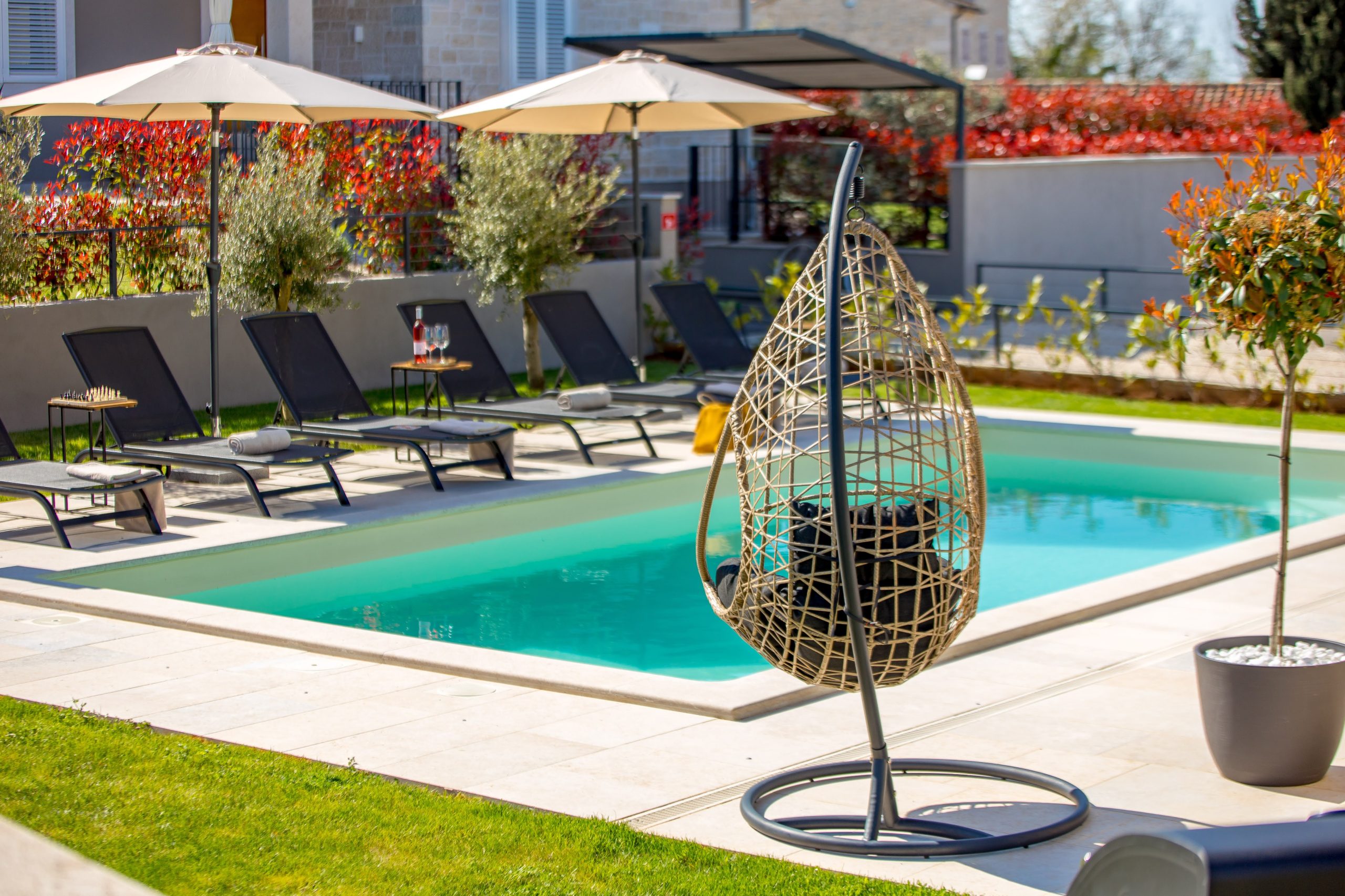 Hanging egg chair by the pool and sun loungers